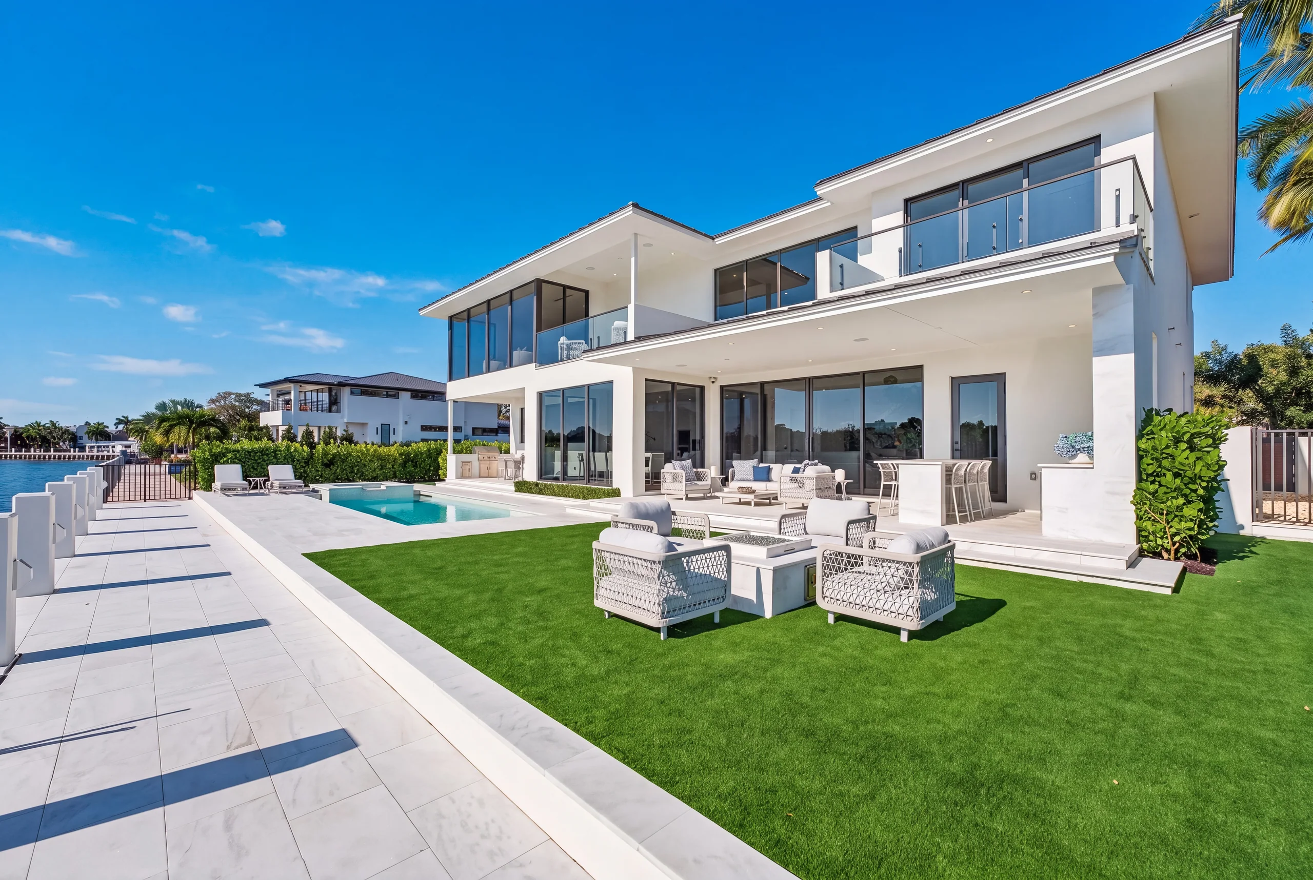 Contemporary waterfront residence with a pool, lawn, and open blue sky